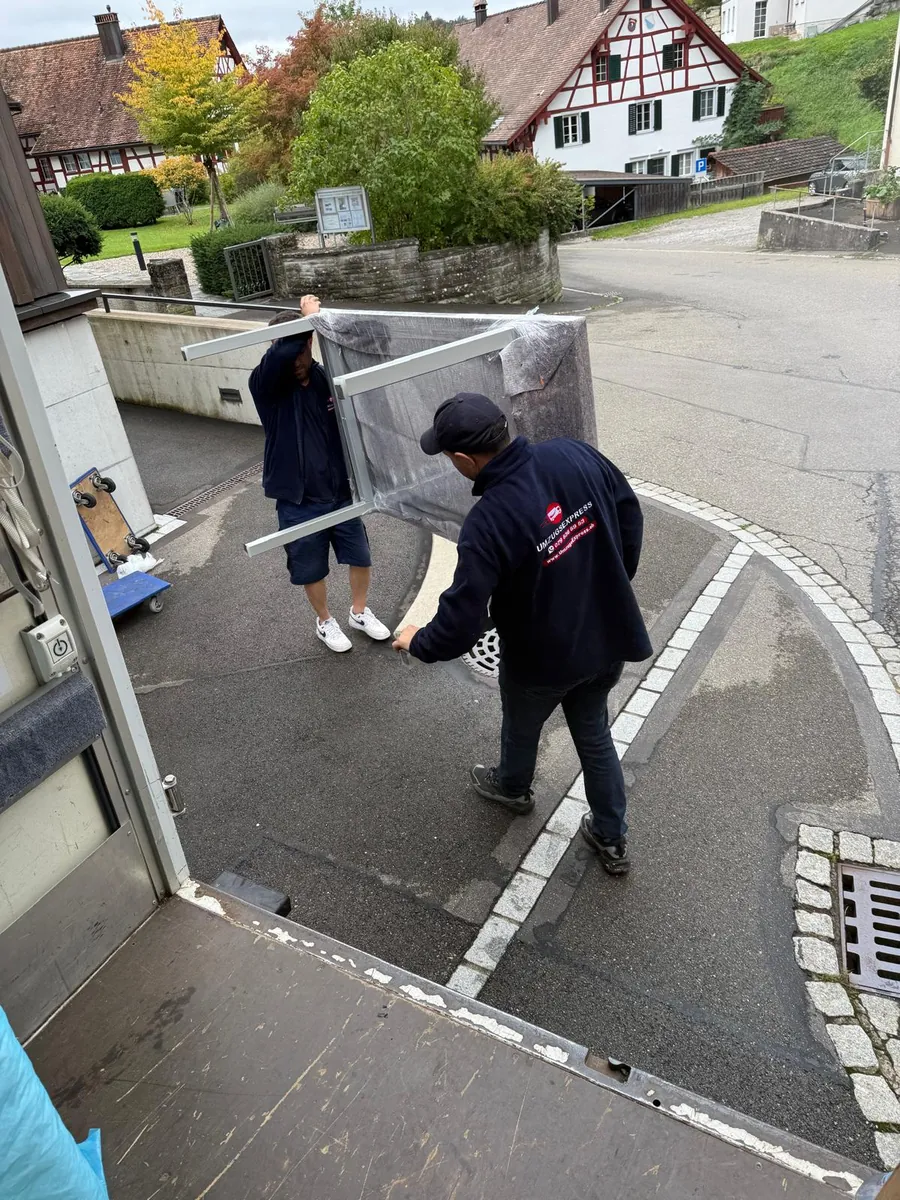 Umzugsexpress job: Two movers carrying a large glass panel to the moving van