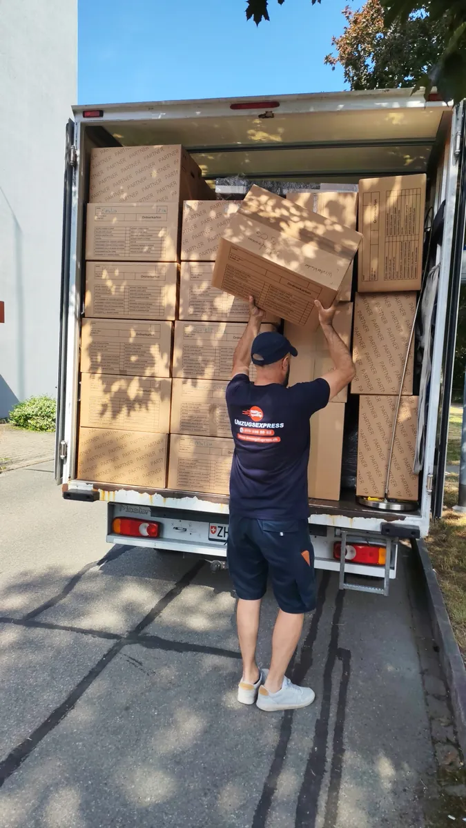 Intervention d’Umzugsexpress : Collaborateur empilant des cartons dans le camion