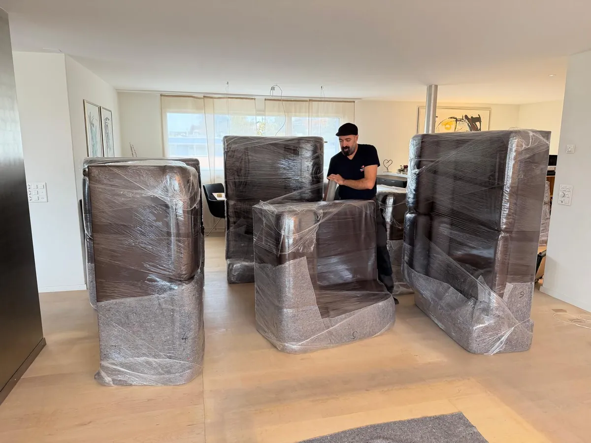Umzugsexpress job: Team member wrapping sofas and armchairs in blankets and stretch film