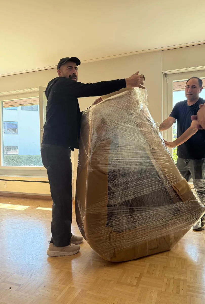 Intervento di Umzugsexpress: Due collaboratori avvolgono una grande poltrona nella pellicola