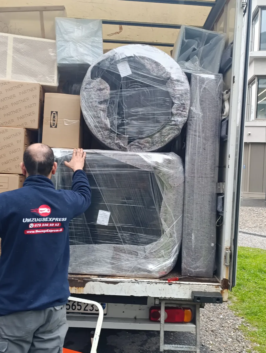 Einsatz von Umzugsexpress: Mitarbeiter sichert verpackte Sessel im Laderaum des Umzugswagens