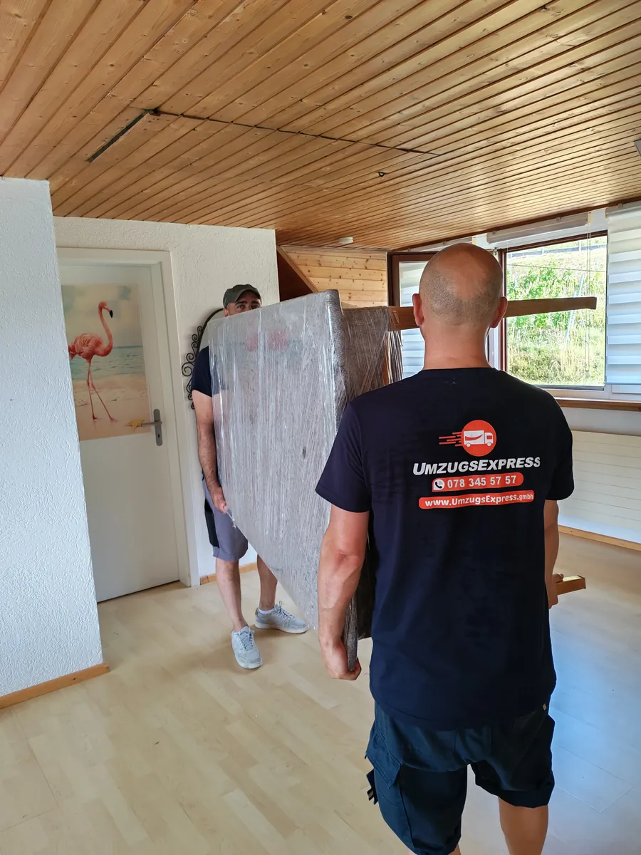 Umzugsexpress job: Two movers carrying a wrapped piece of furniture through the flat