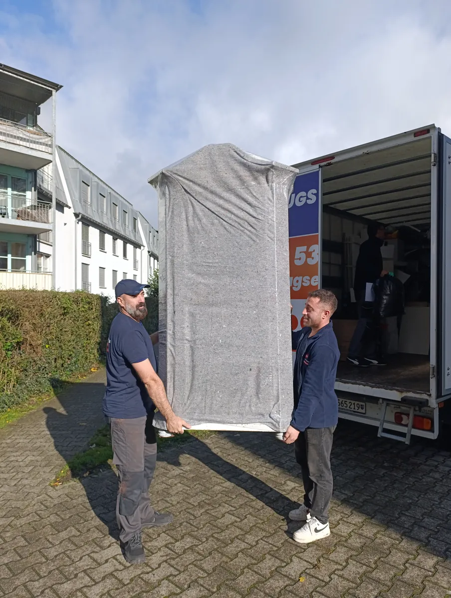 Umzugsexpress job: Move in the Lenzburg area: two team members carry a blanket-wrapped wardrobe to the removal truck